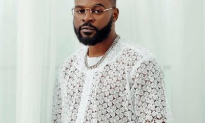 Portrait of a man with a trimmed beard and glasses wearing a white lace shirt and a silver chain.