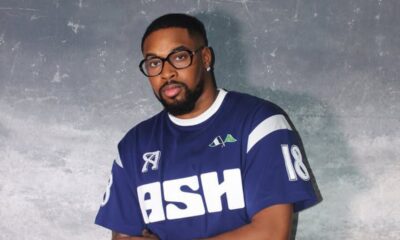 Man with glasses wearing a blue ASH jersey with the number 18, posing against a gray backdrop.