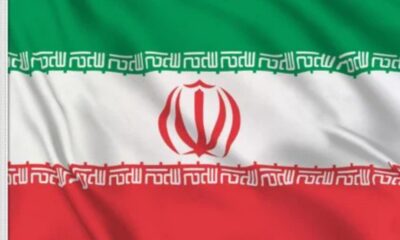 Iran national flag showing green, white, and red stripes with a red emblem in the center and Kufic script along the borders.