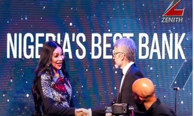 Two professionals shake hands on a stage with a blue backdrop that reads 'NIGERIA'S BEST BANK' and features the Zenith logo.