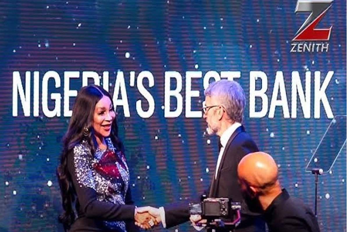 Two professionals shake hands on a stage with a blue backdrop that reads 'NIGERIA'S BEST BANK' and features the Zenith logo.