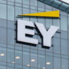Glass-office building facade featuring a large white EY logo with a yellow triangular accent above.