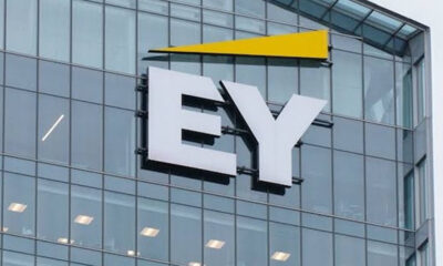 Glass-office building facade featuring a large white EY logo with a yellow triangular accent above.
