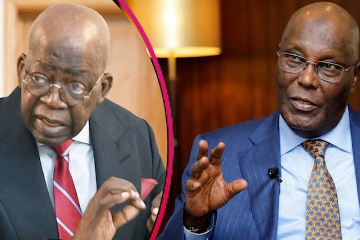 Two suited men in a conversation, left man with red tie and glasses, right man in a blue suit speaking.