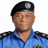 Male police officer in a blue uniform with black epaulettes and a black beret featuring an emblem, facing the camera.