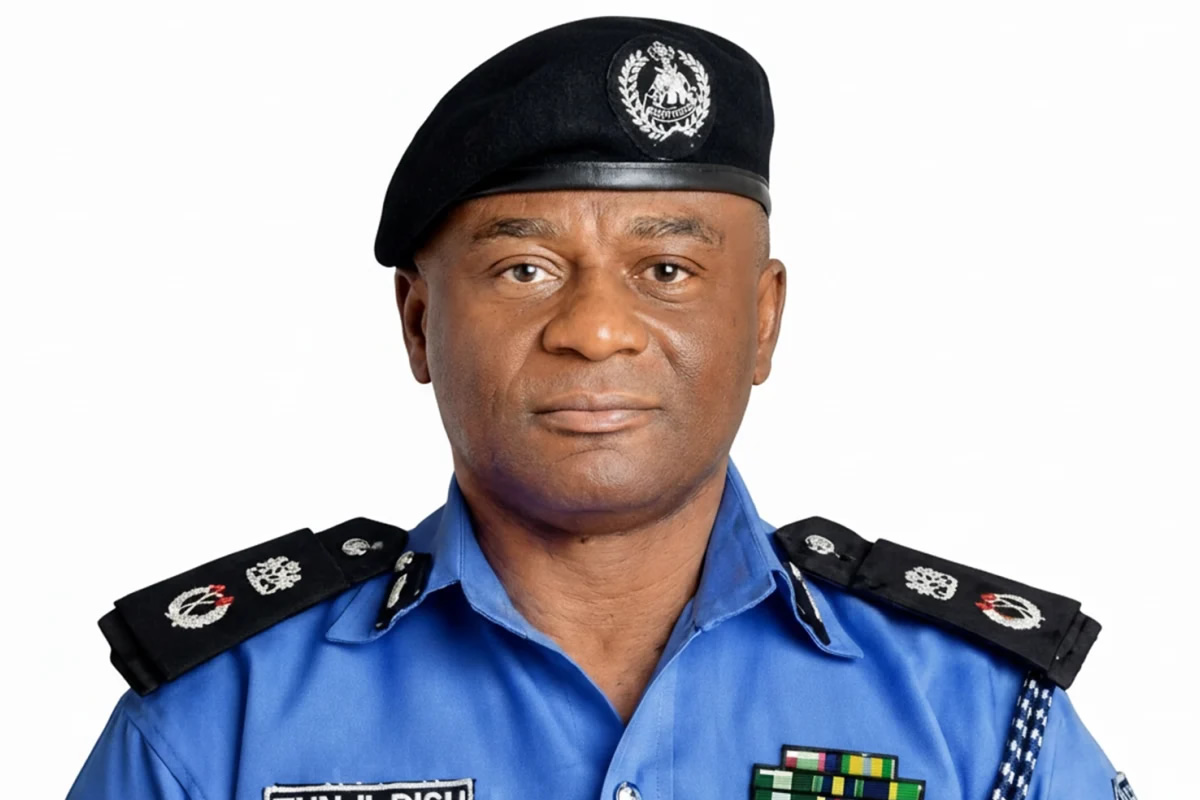 Male police officer in a blue uniform with black epaulettes and a black beret featuring an emblem, facing the camera.