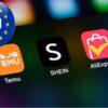Phone home screen showing Temu, SHEIN, and AliExpress apps with an EU badge overlapping the corner.