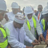 Group of professionals in hard hats and reflective vests building a concrete block together at a construction site
