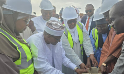 Group of professionals in hard hats and reflective vests building a concrete block together at a construction site