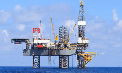Offshore oil rig standing on pilings in the blue ocean under a clear sky.