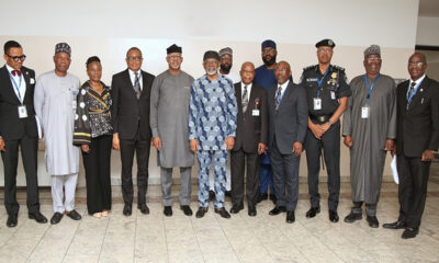 Group of professionals standing in a row for a formal photo indoors, wearing suits and traditional attire.