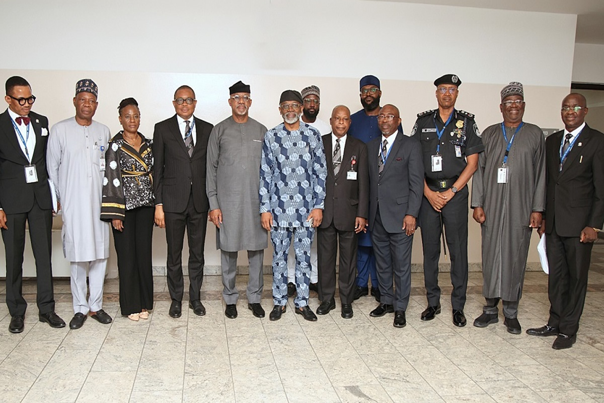 Group of professionals standing in a row for a formal photo indoors, wearing suits and traditional attire.
