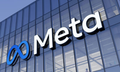 Meta logo with a blue infinity symbol and white letters on a glass office building facade against a blue sky