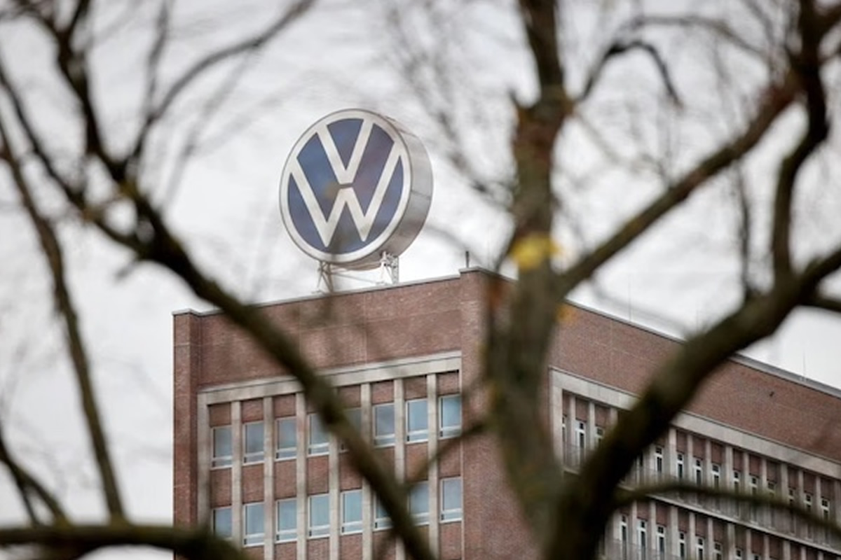 Volkswagen logo on a brick office building, framed by bare tree branches in the foreground.