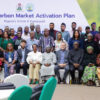 Group photo of diverse attendees at the Nigeria Carbon Market Activation Plan event, banner in the background.