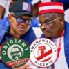 Two men at a political rally wearing round campaign badges for Obidient Movement and Kwankwasiyya Nigeria.