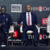 Three men sit on a stage in formal attire during a panel discussion, backdrop shows logos ARISE NEWS and THIS DAY.