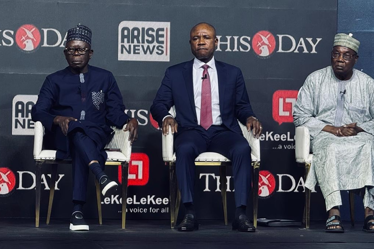 Three men sit on a stage in formal attire during a panel discussion, backdrop shows logos ARISE NEWS and THIS DAY.