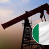 Oil pump jack silhouettes at sunset with a circular Nigerian flag badge in the foreground.