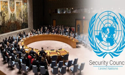 United Nations Security Council meeting around a large circular table with delegates seated; UN emblem on the right.