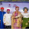 Group of six Nigerian dignitaries in colorful traditional attire posing on a stage at a cultural event.