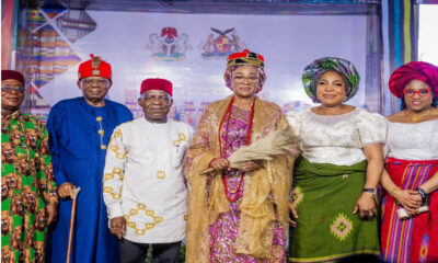 Group of six Nigerian dignitaries in colorful traditional attire posing on a stage at a cultural event.