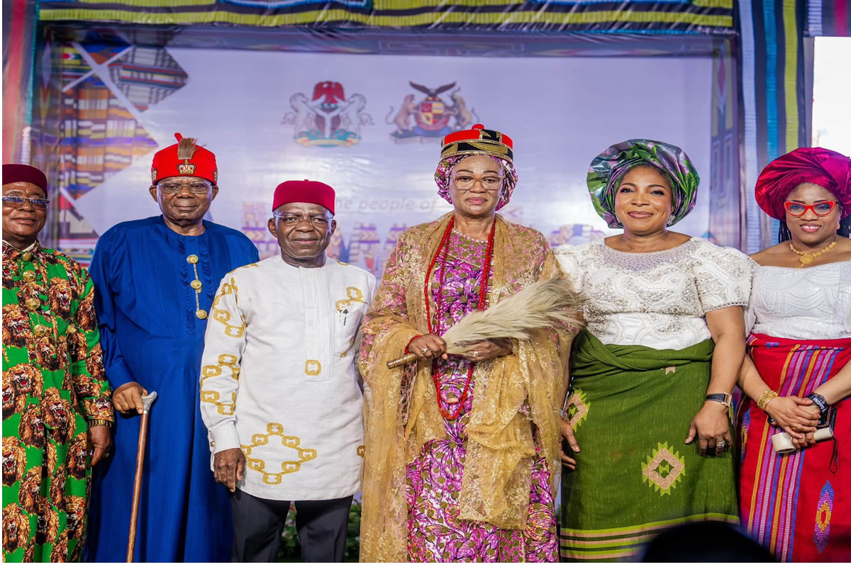 Group of six Nigerian dignitaries in colorful traditional attire posing on a stage at a cultural event.
