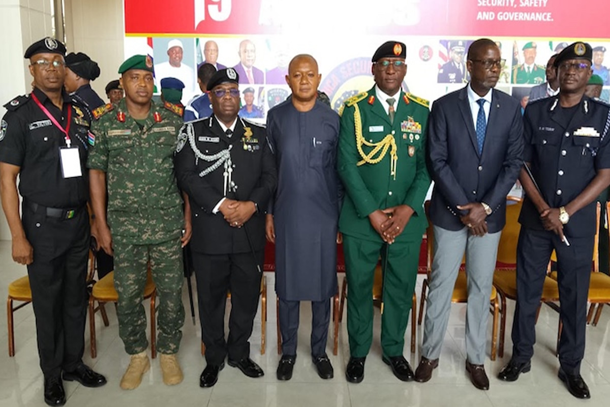 Eight men in military uniforms and a civilian pose for a group photo indoors.