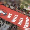Aerial view of a protest with a large red banner bearing the words 'WE WILL KILL TRUMP' held by a crowd along a street. The banner features a black fist logo on the left.