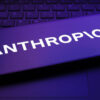 Smartphone screen showing the word ANTHROPIC in bold white letters, illuminated by a purple glow over a keyboard backdrop.
