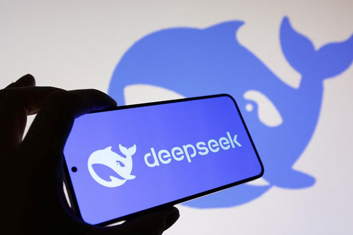 Smartphone showing the Deepseek logo on a blue screen, held in front of a wall with a large blue whale silhouette in the background.