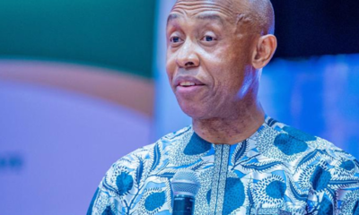 Man in a blue patterned dashiki speaks into a handheld microphone at an event.