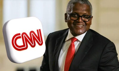 Smiling man in a dark suit and red tie with a large CNN logo foreground.