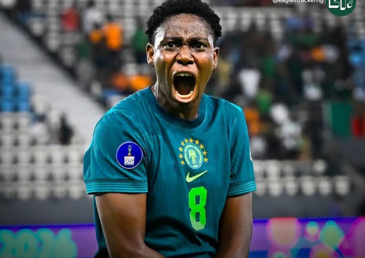 Brazilian soccer player in teal jersey shouting with mouth wide open, stadium crowd in the background