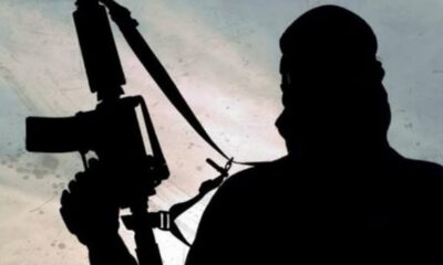 Silhouette of a person holding a rifle on their shoulder, facing left, against a cloudy sky.