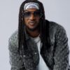Man with long braids, bandana headband, and oversized sunglasses, wearing a floral-pattern denim jacket.