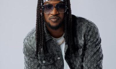 Man with long braids, bandana headband, and oversized sunglasses, wearing a floral-pattern denim jacket.