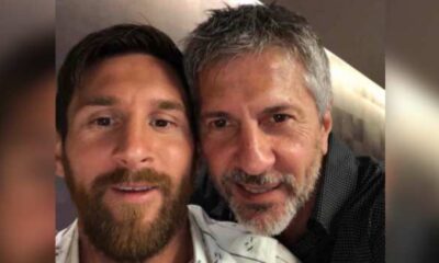 Two men smiling for a close-up selfie, faces side by side indoors.