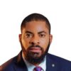 Professional headshot: man with a full beard in a navy suit and red tie against a white background