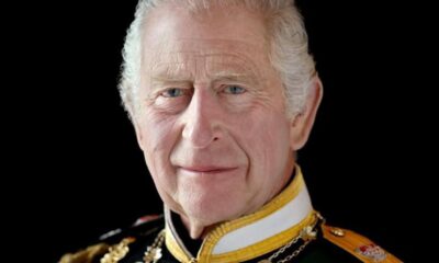 Older man in ceremonial military uniform with gold braid and medals against a black background.