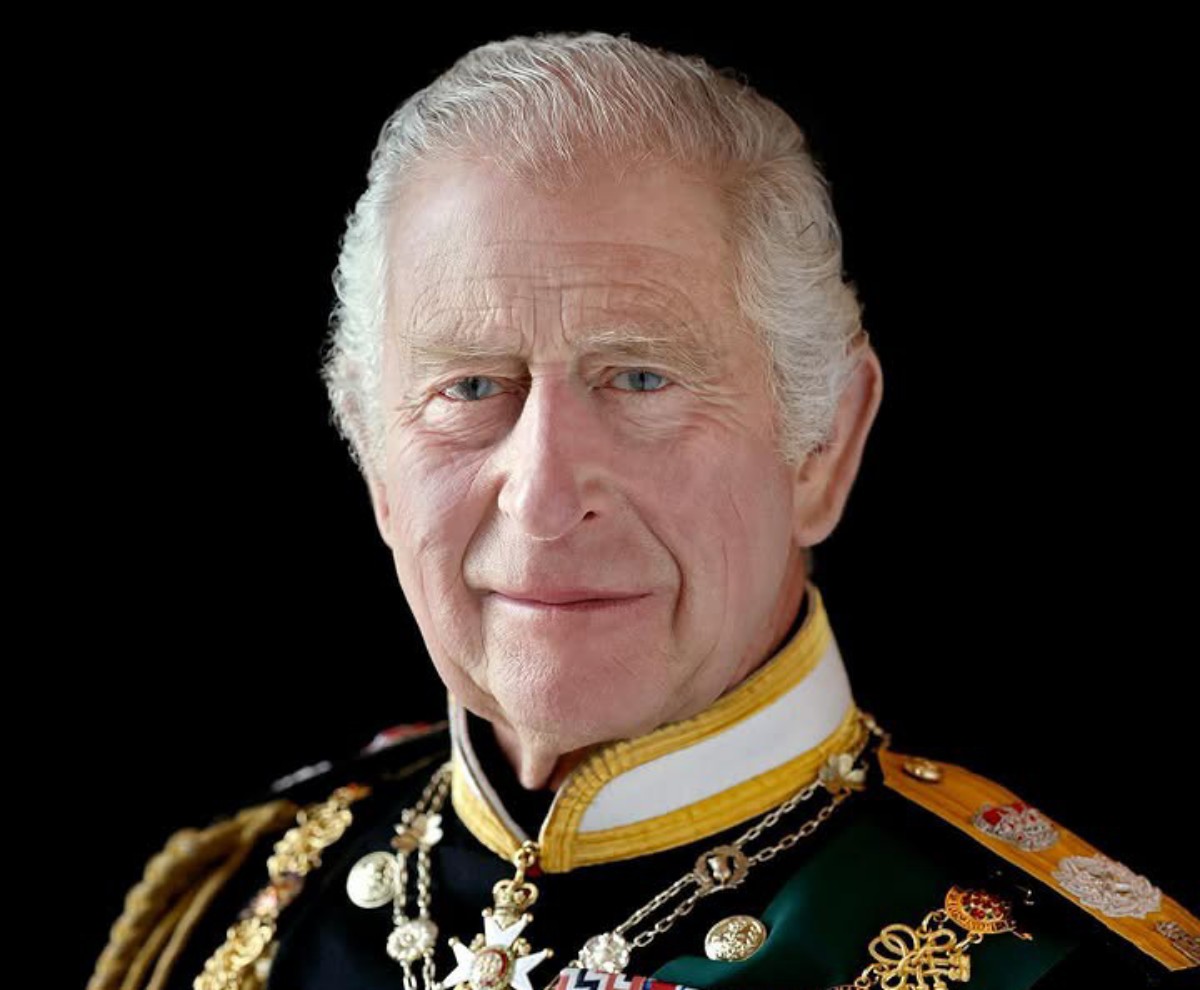 Older man in ceremonial military uniform with gold braid and medals against a black background.