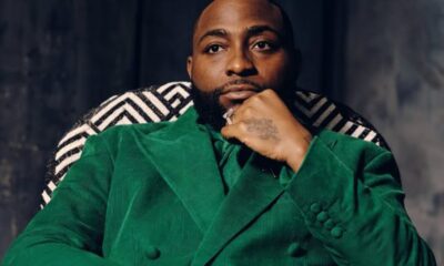 Portrait of a man in a green velvet suit, seated with chin resting on his hand, looking at the camera.