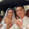 Bride and groom showing their wedding rings while sitting in a car, smiling at the camera.