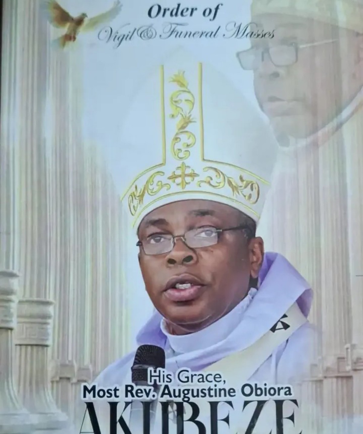 Catholic bishop speaking into a microphone, wearing an ornate white and gold mitre and purple vestments, with church columns in the background (text reads 'His Grace, Most Rev. Augustine Obiora Akubeze')