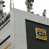 Corner of a modern building with MTN logo on a dark panel and a cluster of satellite dishes and antennas on the roof, indicating a telecom facility
