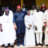 Group of people in traditional Nigerian attire posing on steps for a formal group photo.