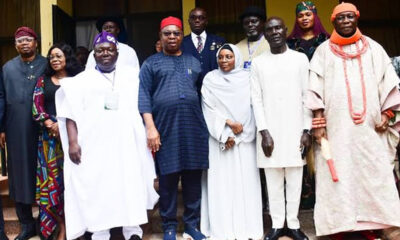 Group of people in traditional Nigerian attire posing on steps for a formal group photo.