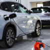 Electric SUV in a showroom plugged into a charging cable with other cars on display in the background.