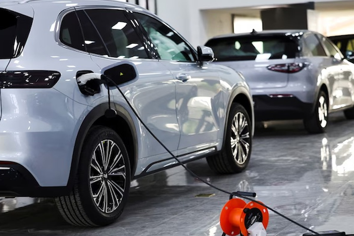 Electric SUV in a showroom plugged into a charging cable with other cars on display in the background.