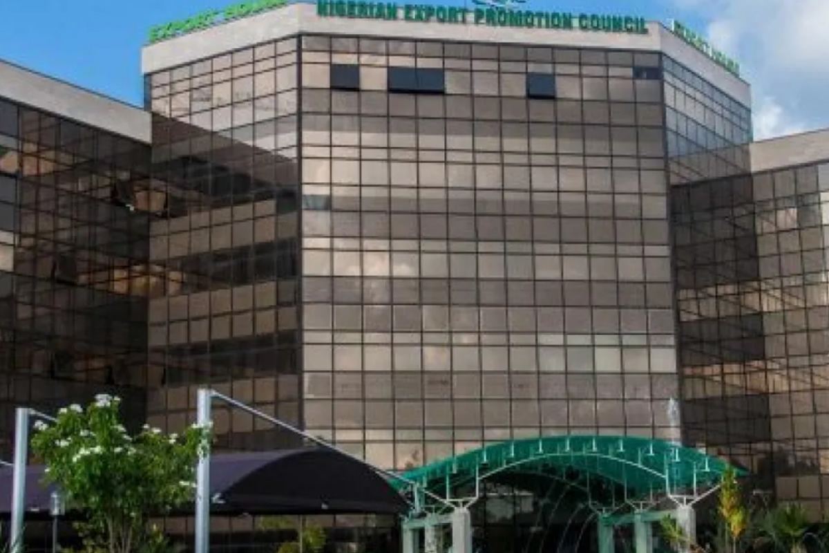 Glass-front office building with reflective panels and a green arched walkway to the entrance.